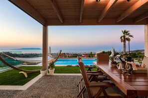 A wooden deck with a pool, outdoor seating, and a view of the ocean. - Villa GG (Hersonissos)