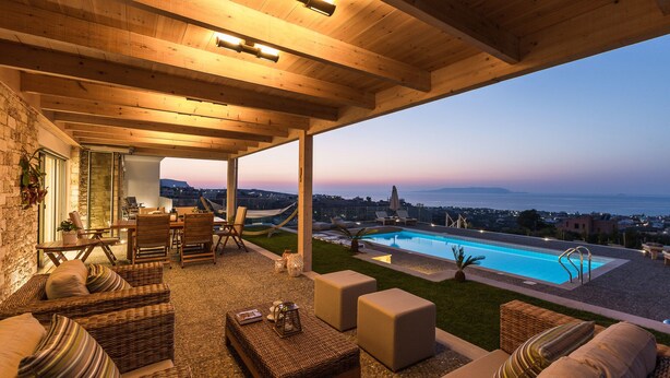 Un espacio de estar techado al aire libre con muebles de mimbre, piscina y vista al mar.