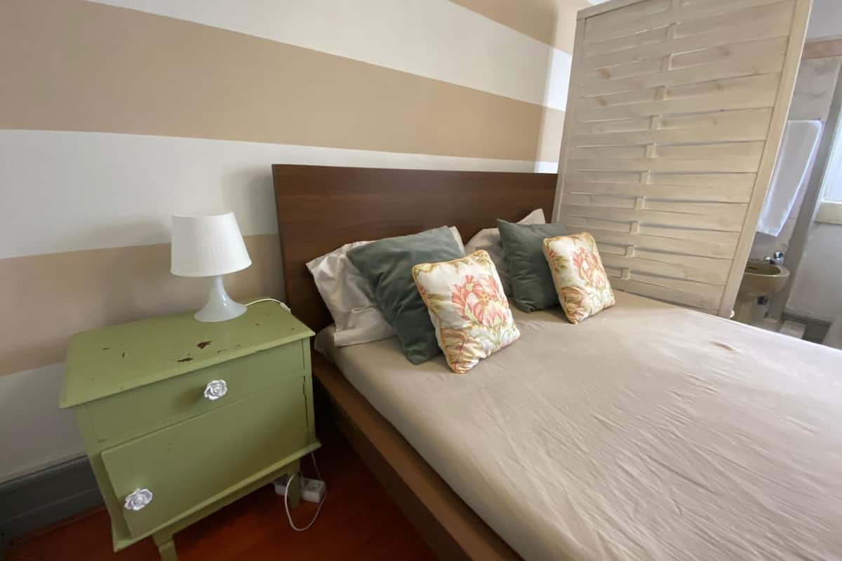 Ein Schlafzimmer mit Bett, Kissen, Nachttisch und Lampe.