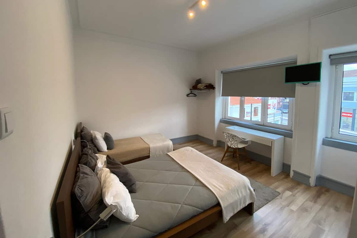 Ein Schlafzimmer mit Bett, Schreibtisch, Stuhl, Fernseher und einem Fenster mit Aussicht.