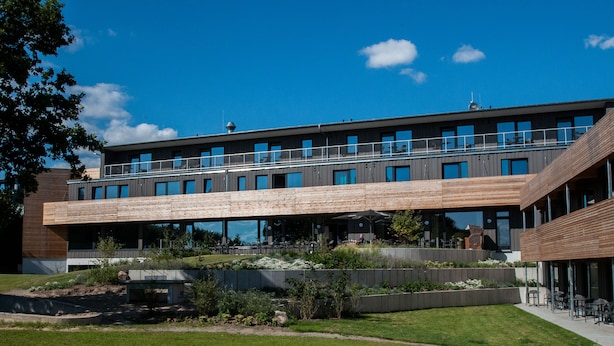 A modern building with a flat roof, large windows, and a covered outdoor area with seating. - Strandkind - Dein Ostseehotel (Neustadt in Holstein)
