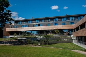 A modern building with a flat roof, large windows, and a covered outdoor area with seating. - Strandkind - Dein Ostseehotel (Neustadt in Holstein)