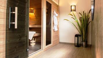 A wooden interior with a sauna room, a potted plant, and a wall-mounted light fixture.