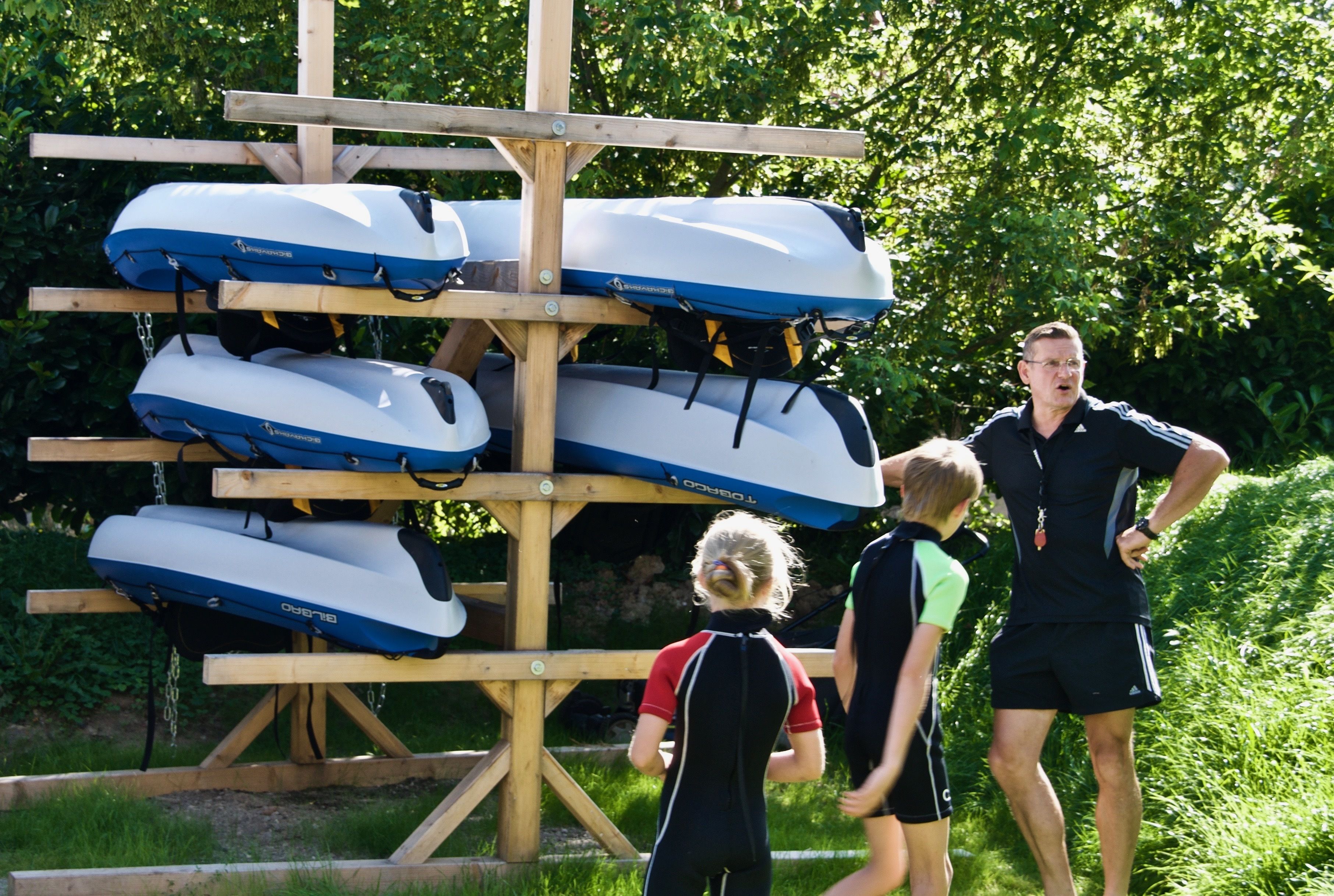Un support en bois contenant plusieurs kayaks blancs et bleus.