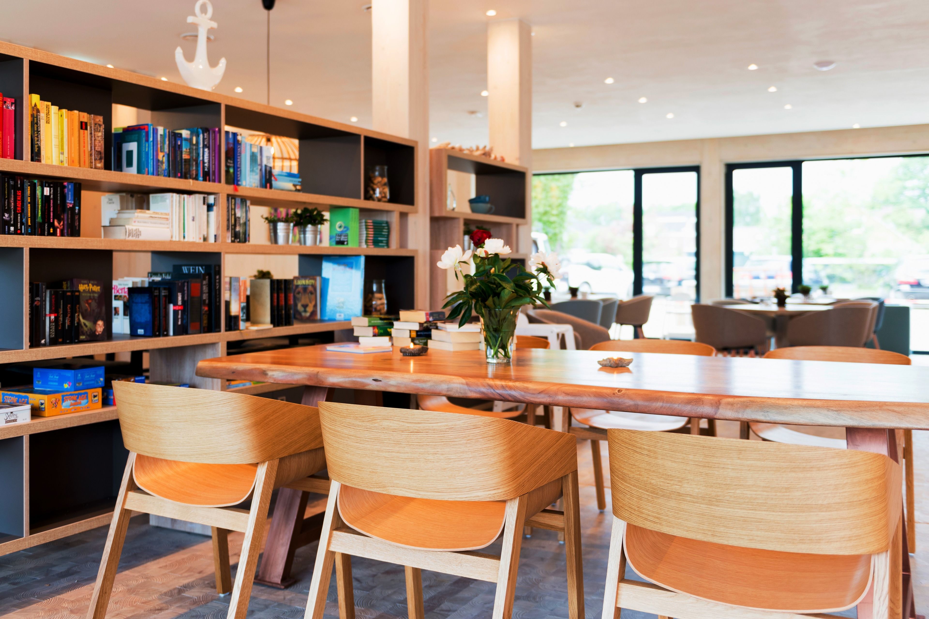 A modern library with wooden bookshelves, a central table, and comfortable seating.