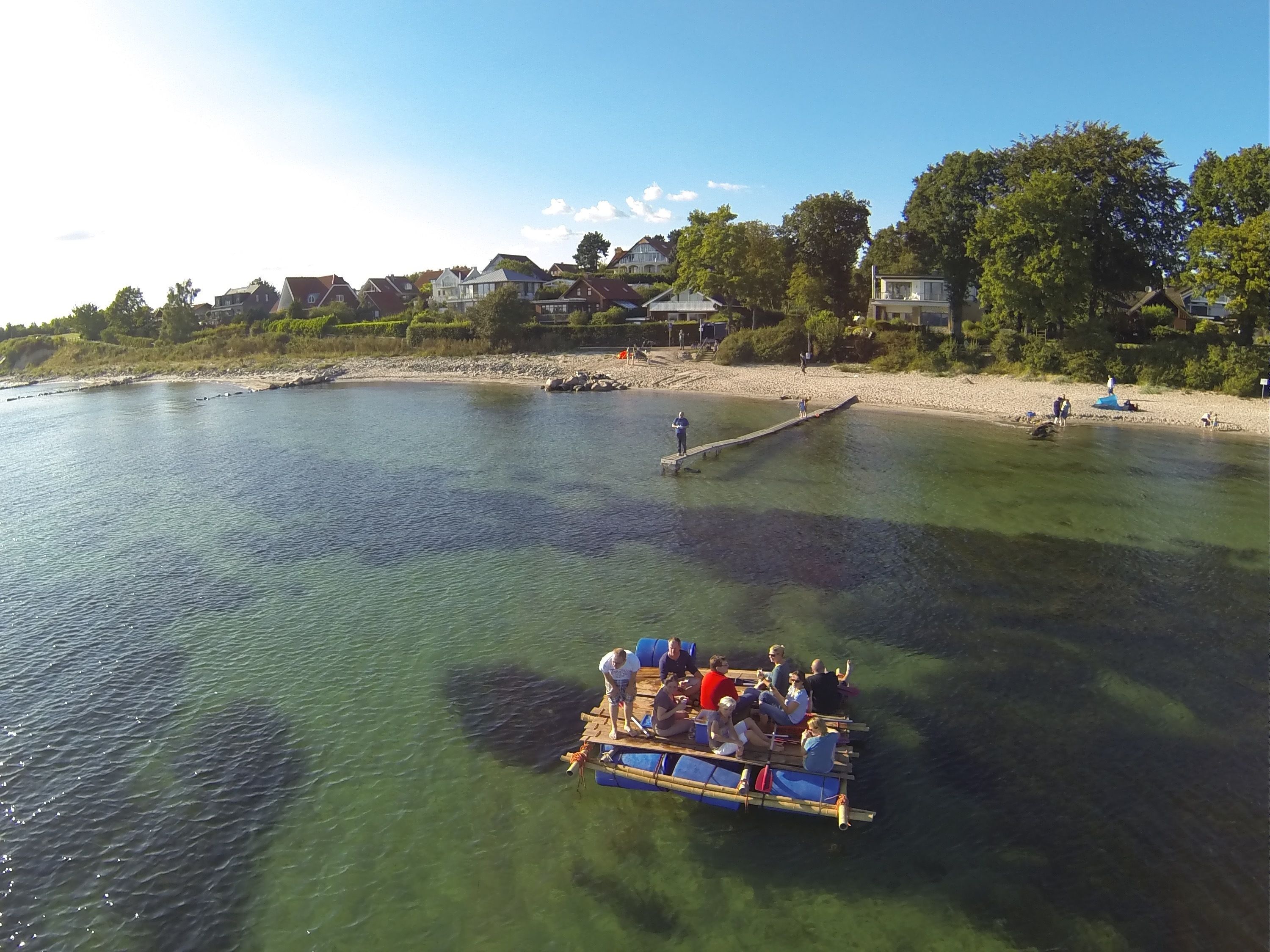 A boat with people on it near a beach with houses in the background.