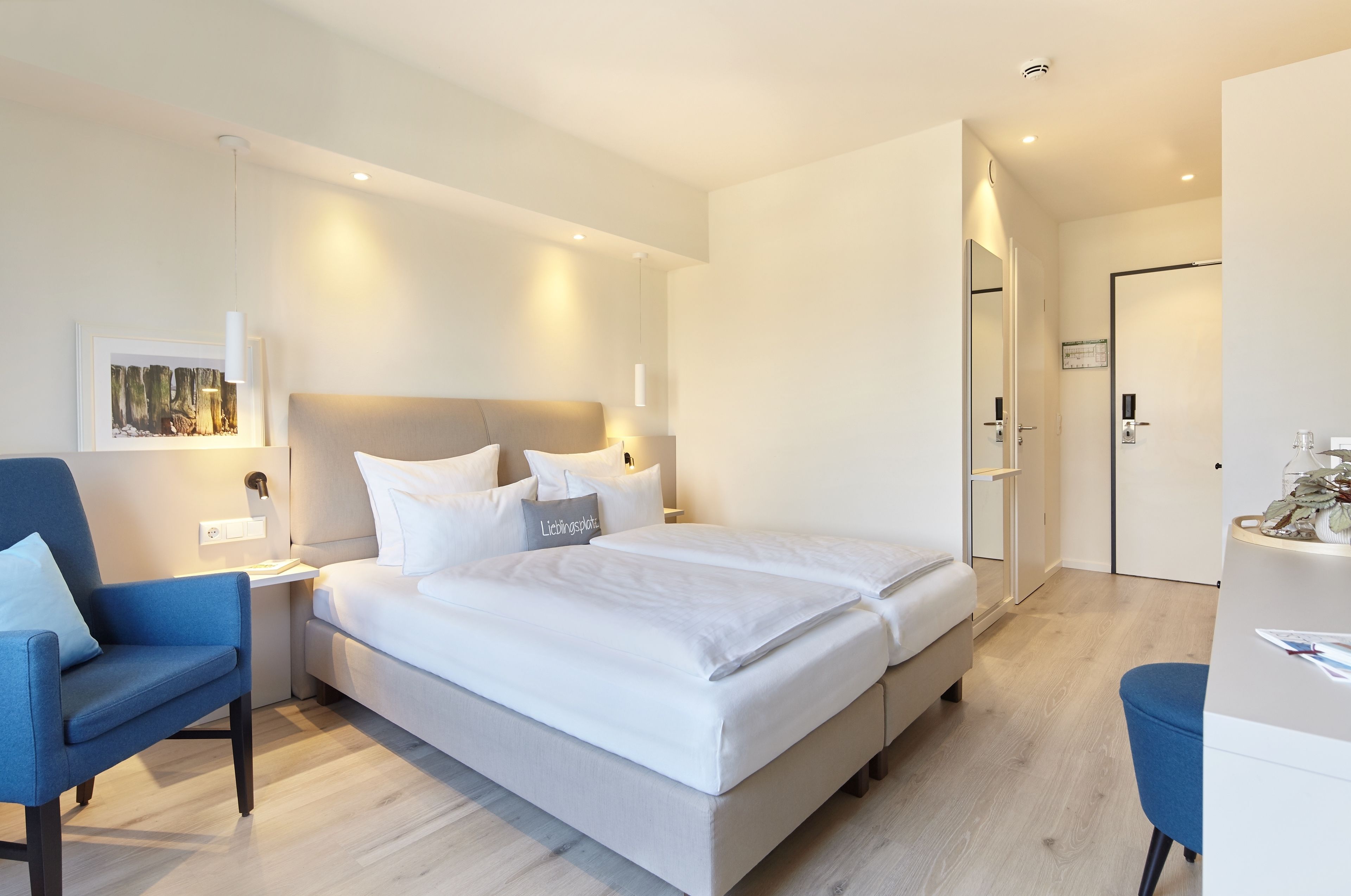 Una camera d'albergo moderna con un letto grande, una scrivania e una sedia.