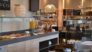 A breakfast buffet with various food items, a coffee machine, and a decorative hanging light. - Strandkind - Dein Ostseehotel (Neustadt in Holstein)