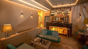 Una sala moderna con un sofá, una mesa de centro y una zona de cocina con taburetes de bar.