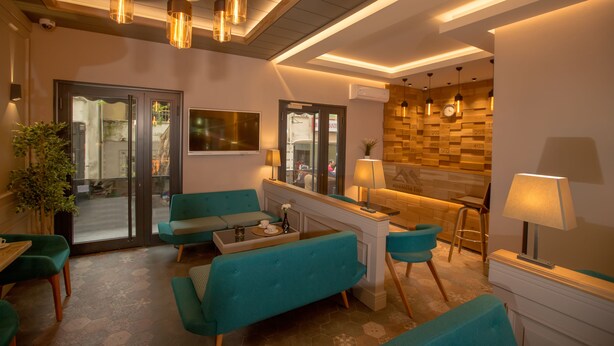 Un moderno vestíbulo de hotel con sofás color turquesa, una mesa de centro, iluminación colgante y una pared de acento de madera.