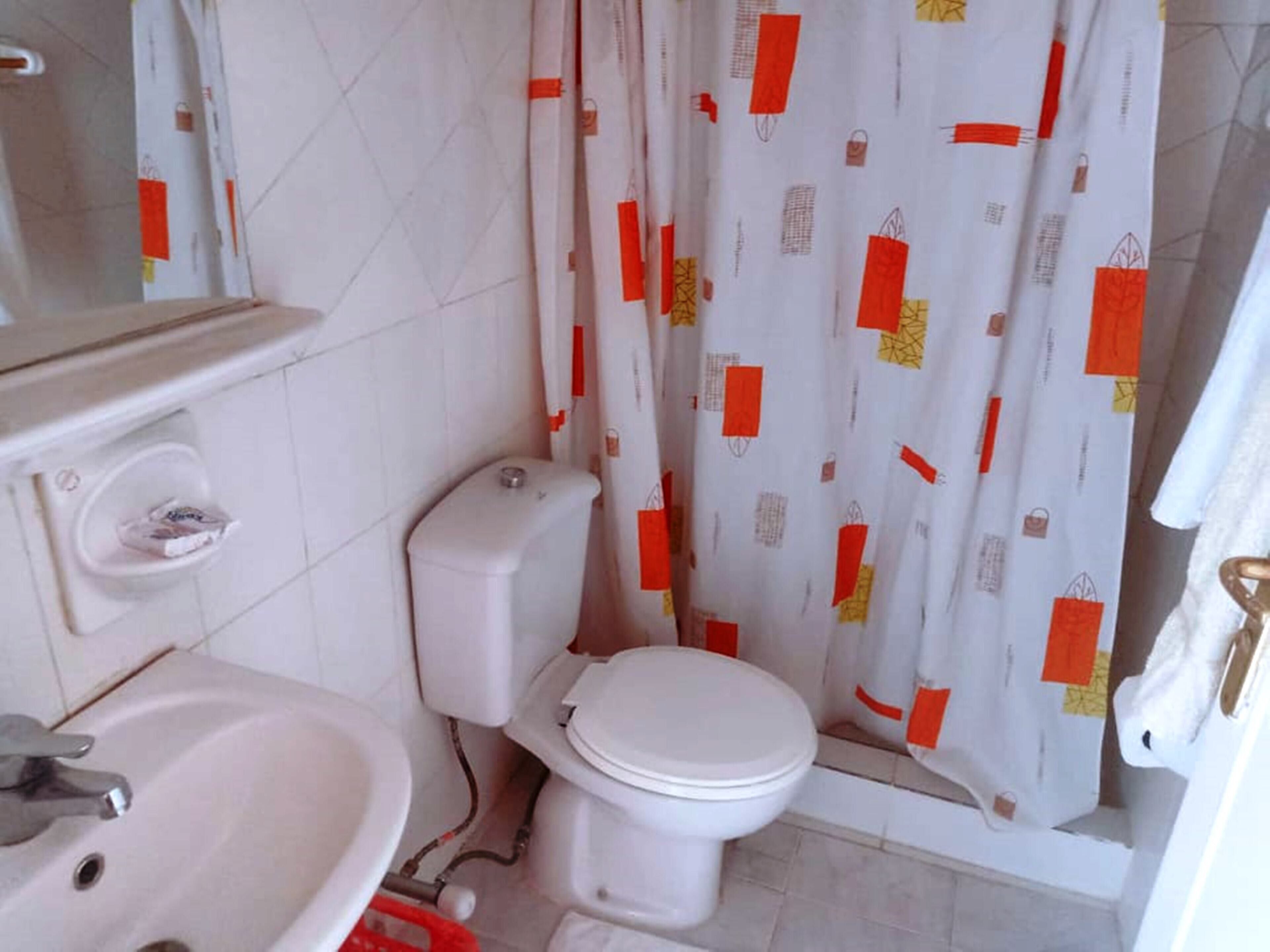 A bathroom with a toilet, sink, and shower curtain.