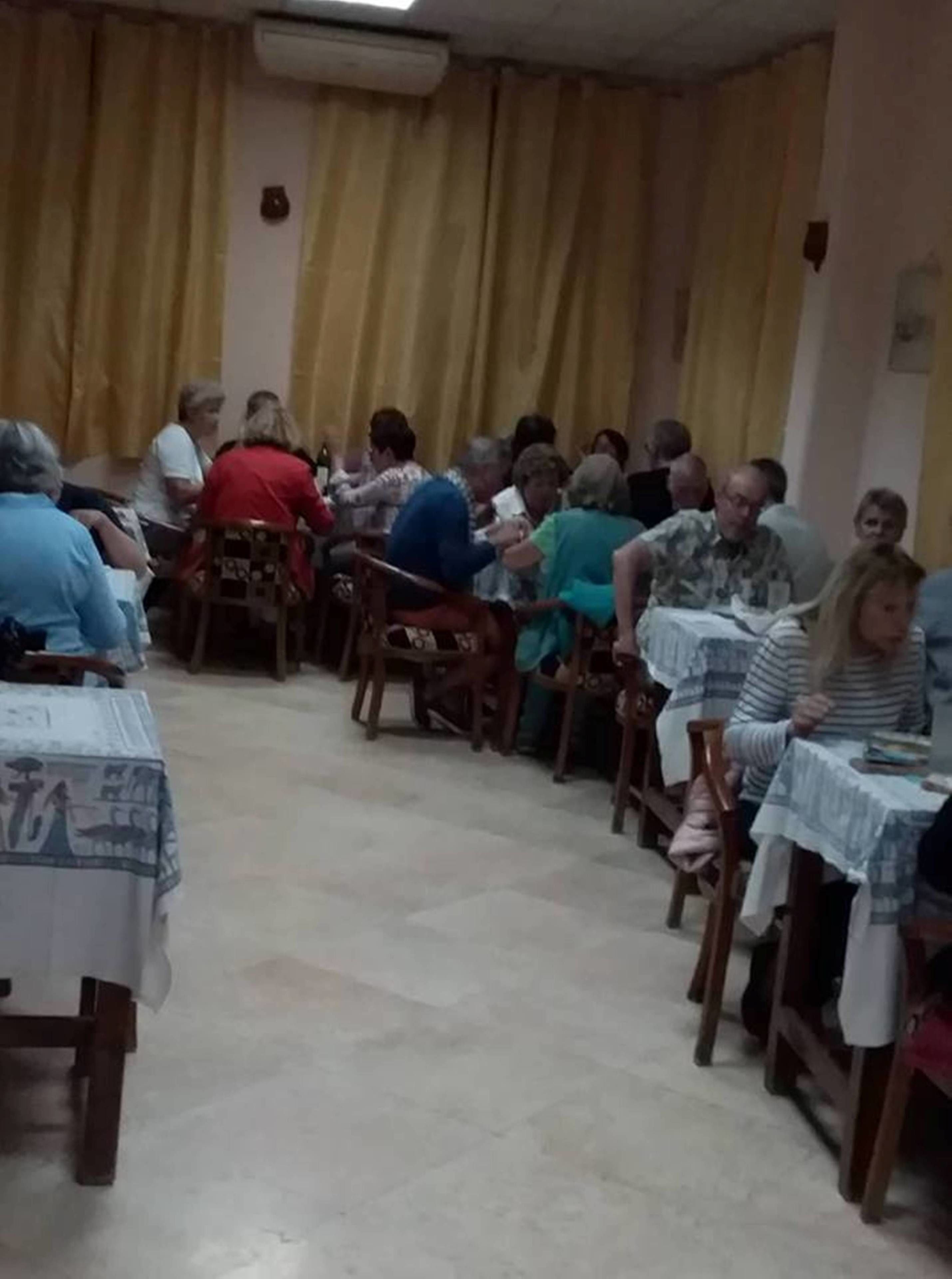 Un salón con sillas y mesas de madera dispuestas en filas, ideal para reuniones o clases grupales.