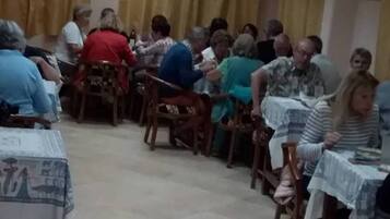 Un salón con sillas y mesas de madera dispuestas en filas, ideal para reuniones o clases grupales.