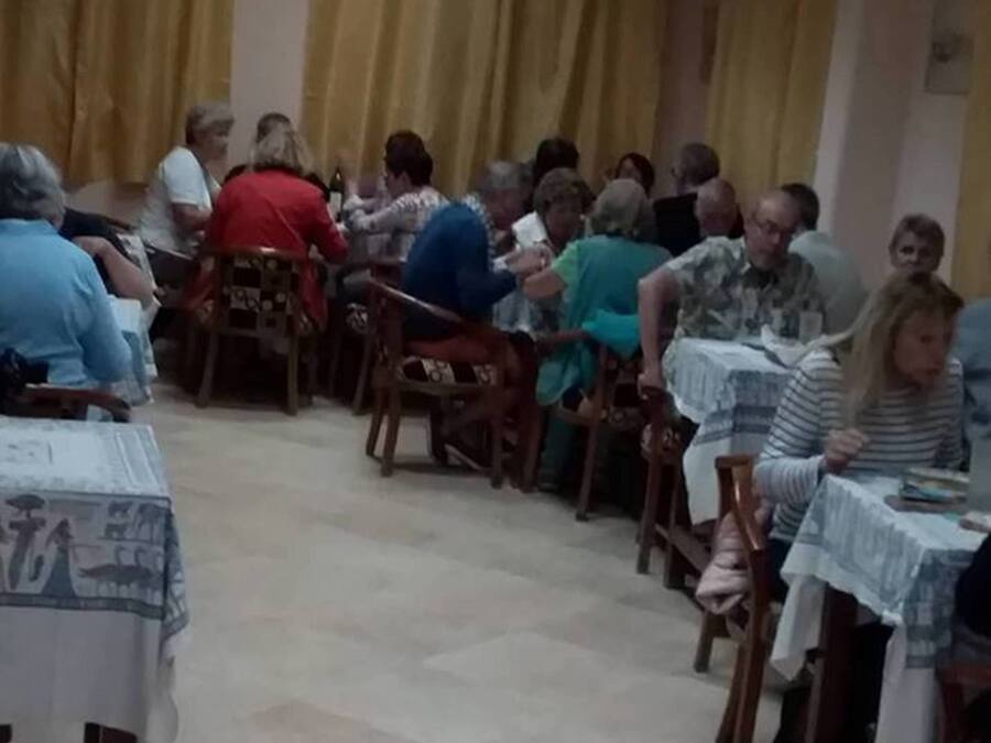 Un salón con sillas y mesas de madera dispuestas en filas, ideal para reuniones o clases grupales.