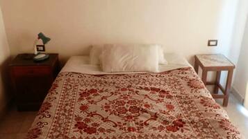 A bedroom with a bed, a nightstand, a lamp, and a wall-mounted light fixture.