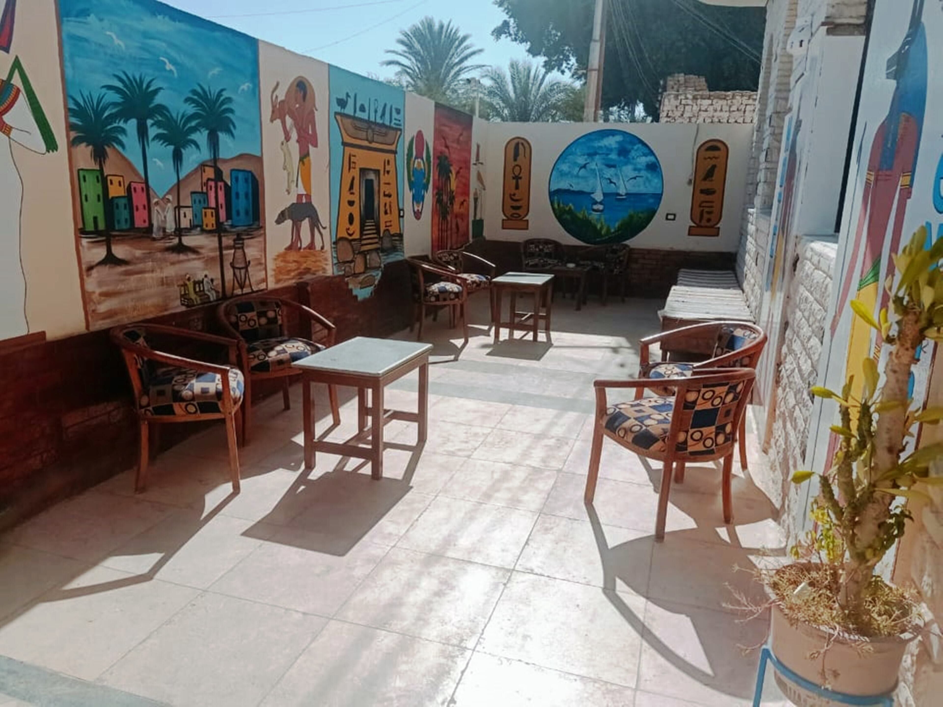 A sunlit outdoor seating area with wooden furniture and a mural on the wall.