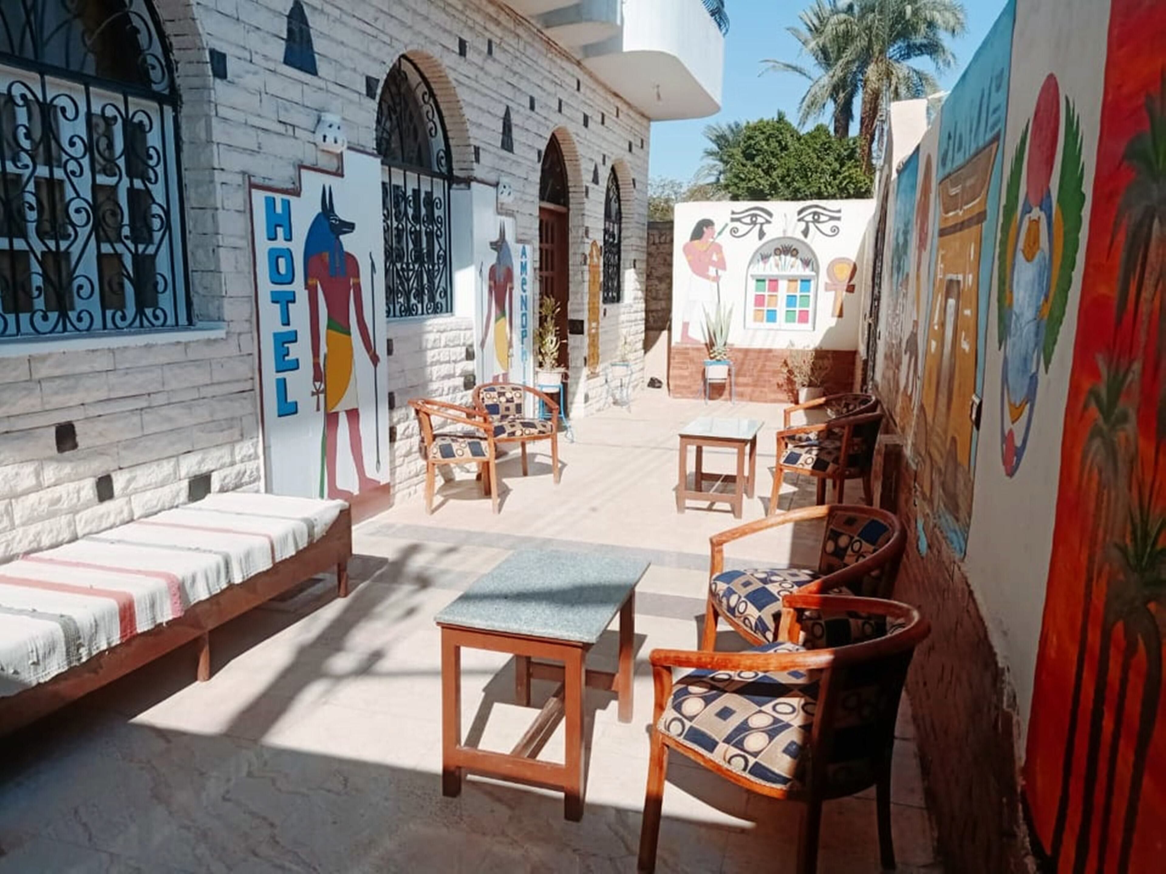 A hotel courtyard with outdoor seating, a bed, and colorful murals on the walls.