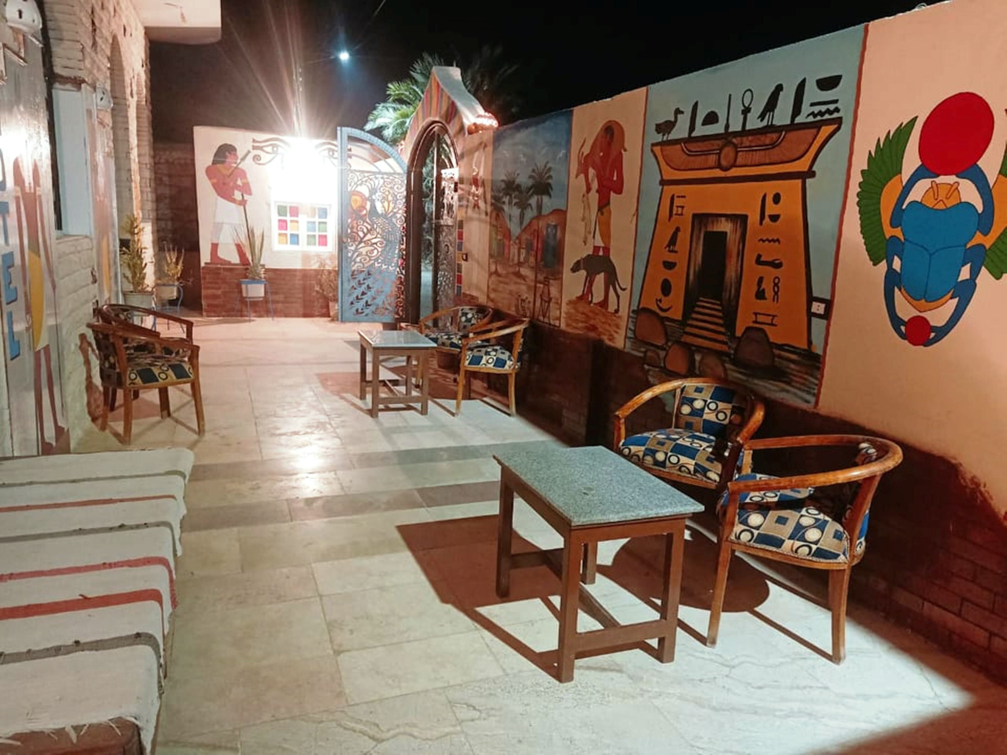 Una habitación con suelo de baldosas, muebles de madera y un mural con arte del antiguo Egipto.