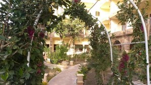 A pathway leading through a courtyard with a pergola, surrounded by greenery and a building with balconies. - Thebes Hotel Luxor (Luxor)
