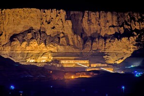 A cave with illuminated structures and a large rock formation. - Thebes Hotel Luxor (Luxor)