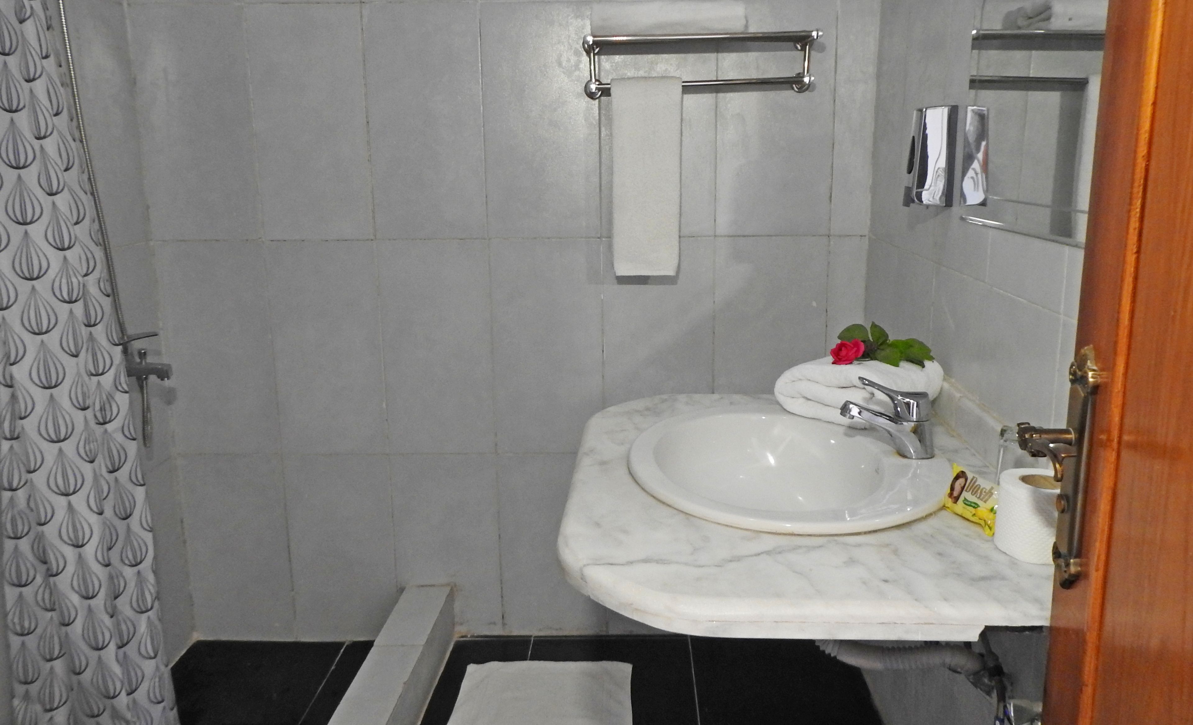 A bathroom with a white sink, a towel rack, and a shower curtain.