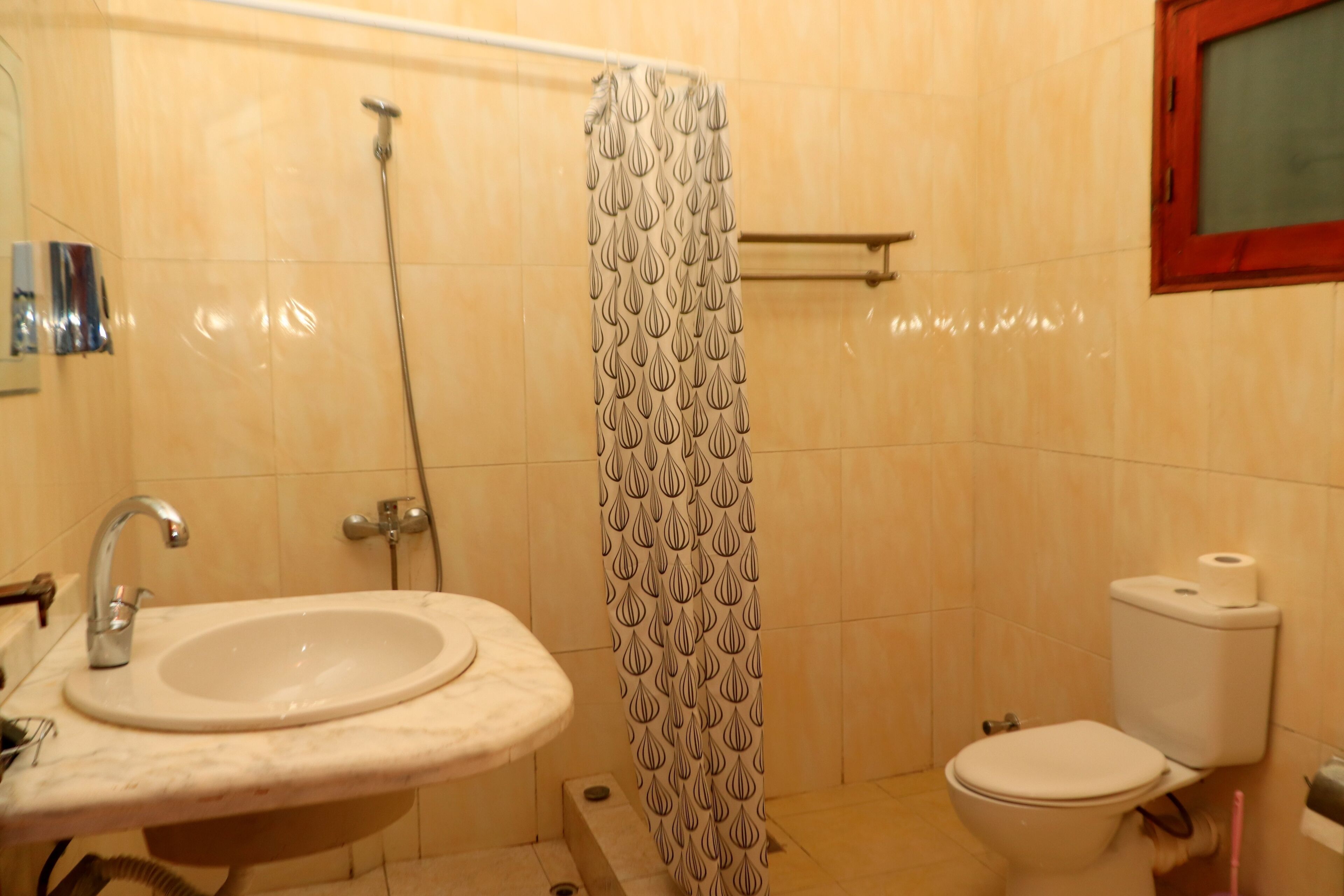 Un baño con lavamanos, inodoro, ducha y un perchero para toallas.