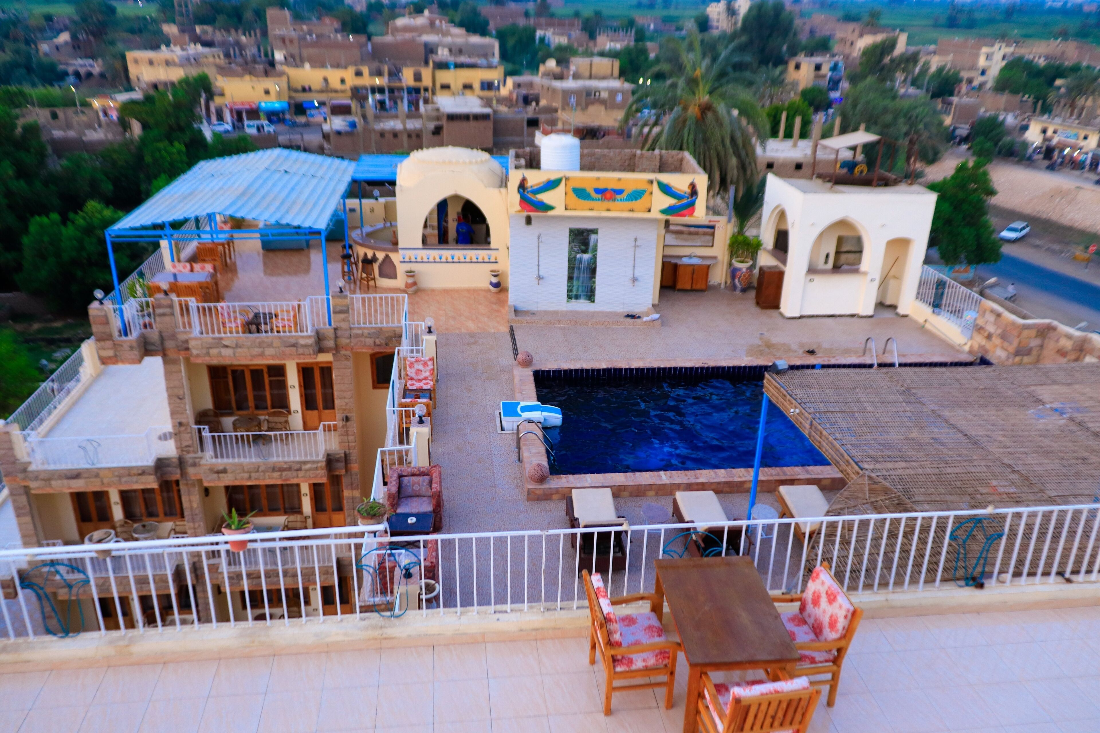 A rooftop pool area with a swimming pool, lounge chairs, and a small table.