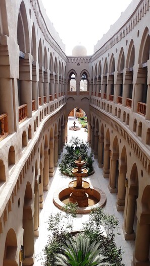 A courtyard with a central fountain, surrounded by arches and columns, leading to a dome structure. - Embrace Hotel (Luxor)