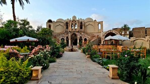 A courtyard with a central fountain, surrounded by outdoor seating and a historic building with arches. - Embrace Hotel (Luxor)
