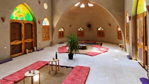 A spacious interior with high arched ceilings, a central seating area with red cushions, and a potted plant. - Embrace Hotel (Luxor)