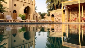 A pool area with lounge chairs and a reflection of a building with arches and domes. - Embrace Hotel (Luxor)