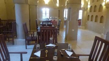 Un espace repas avec une longue table dressée pour six personnes, entourée de chaises en bois.
