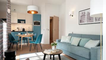 A modern living room with a sofa, a coffee table with a book, and a dining area with chairs and a table.