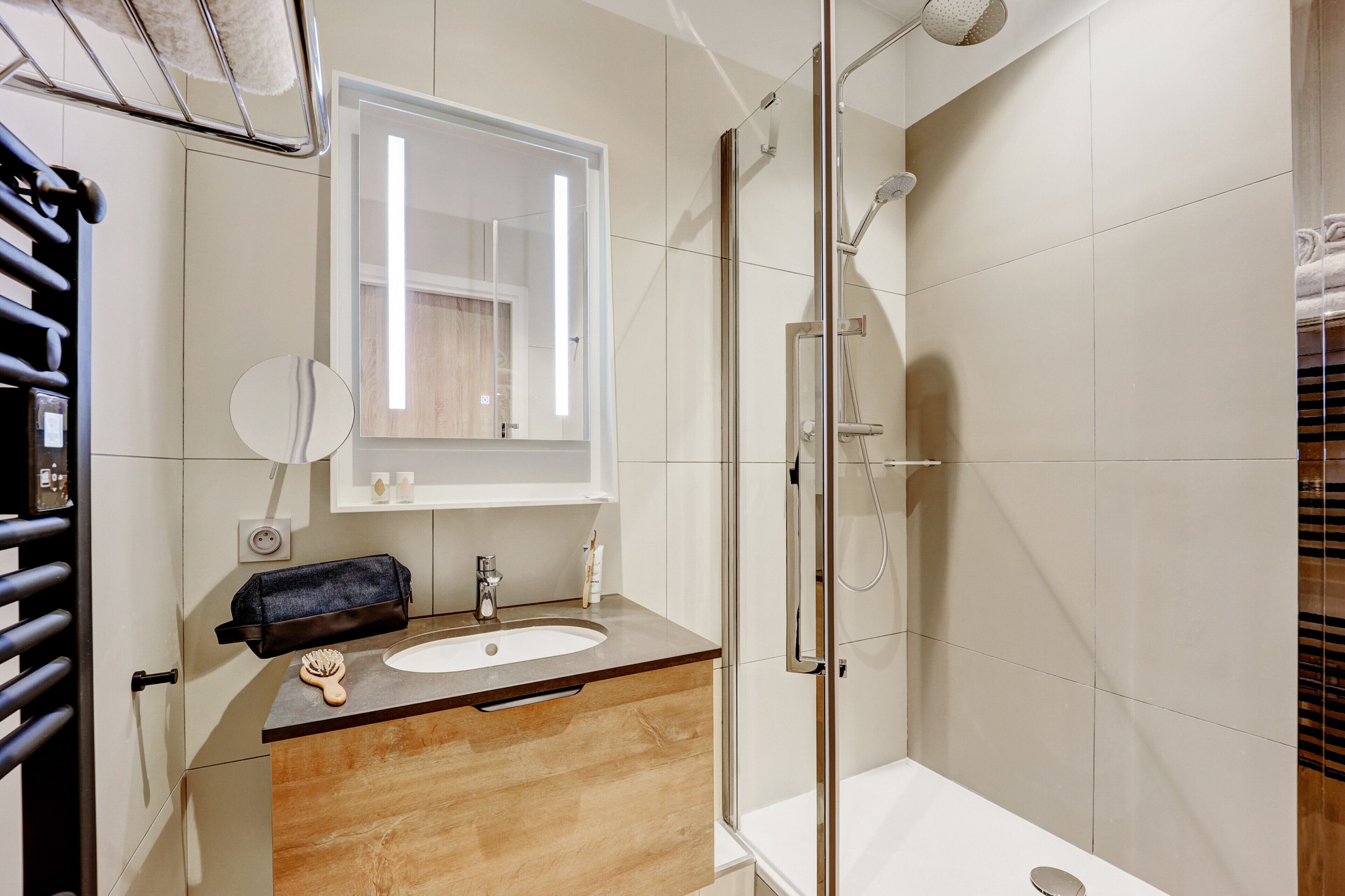 A modern bathroom with a glass-enclosed shower, a wooden vanity with a sink, and a large mirror above the vanity.