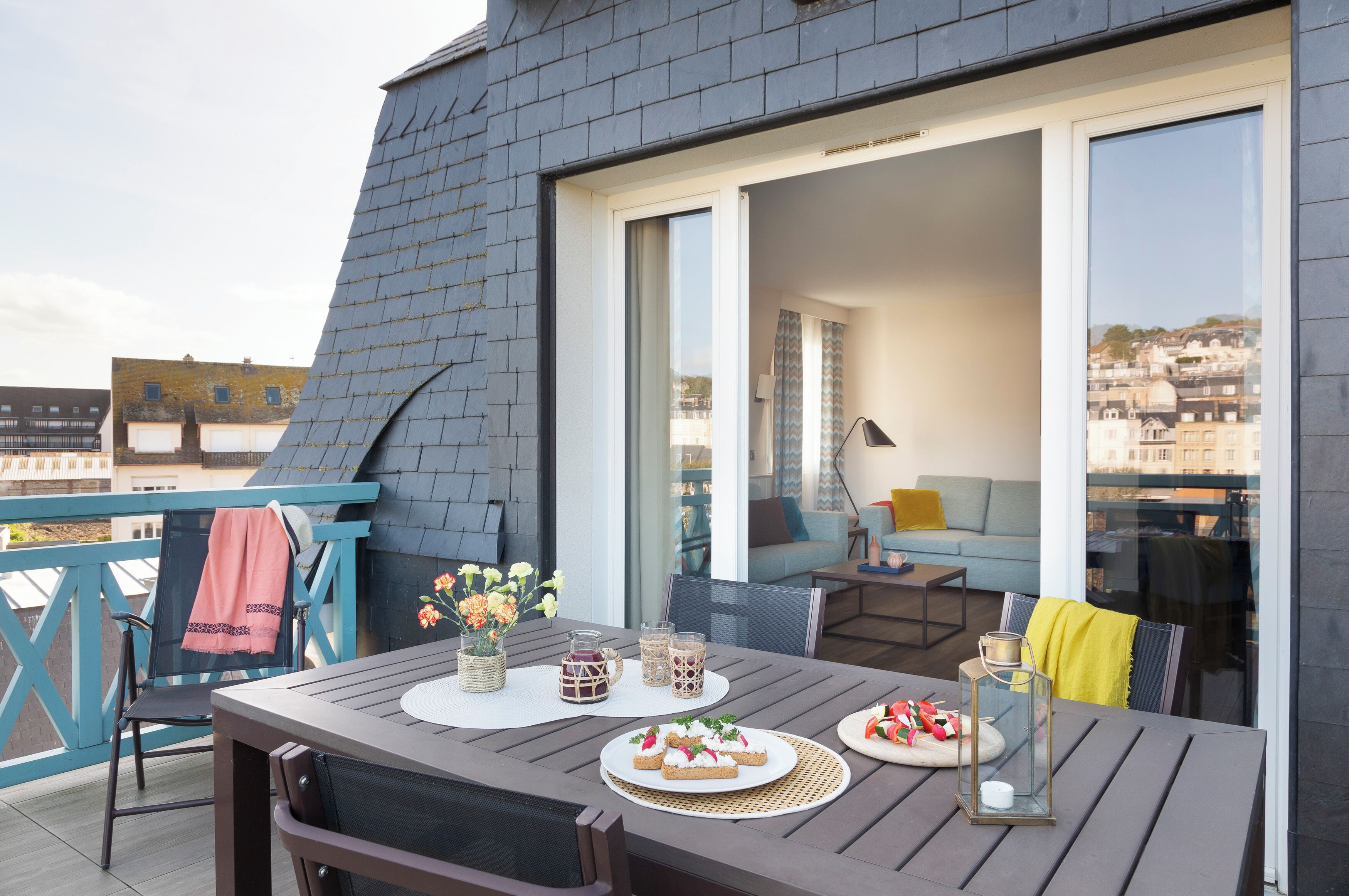 Eine Dachterrasse mit Esstisch, einer Couch und einem Sessel.