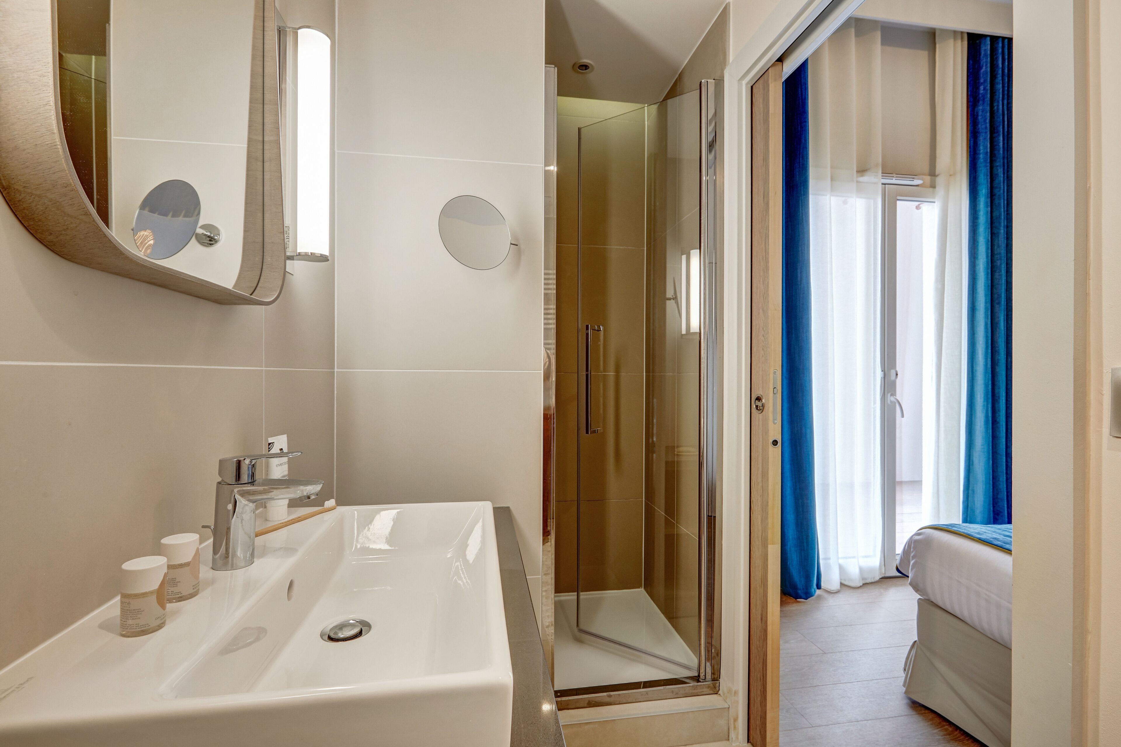 Un baño moderno con un espejo grande, un lavabo doble y una ducha con mampara de vidrio.