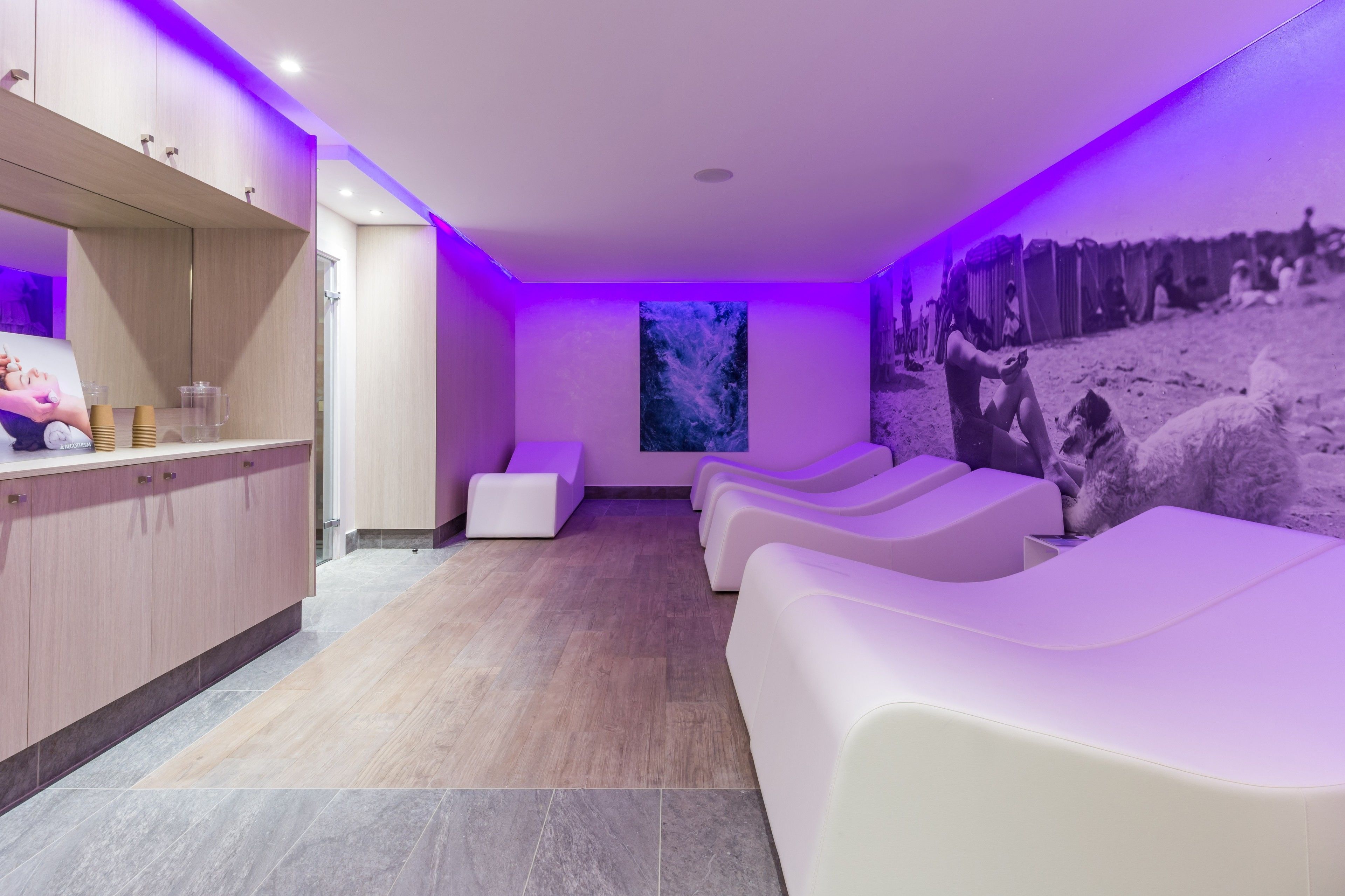 Ein moderner Spa-Bereich mit Empfang, Massagesesseln und einer großen Wandmalerei.