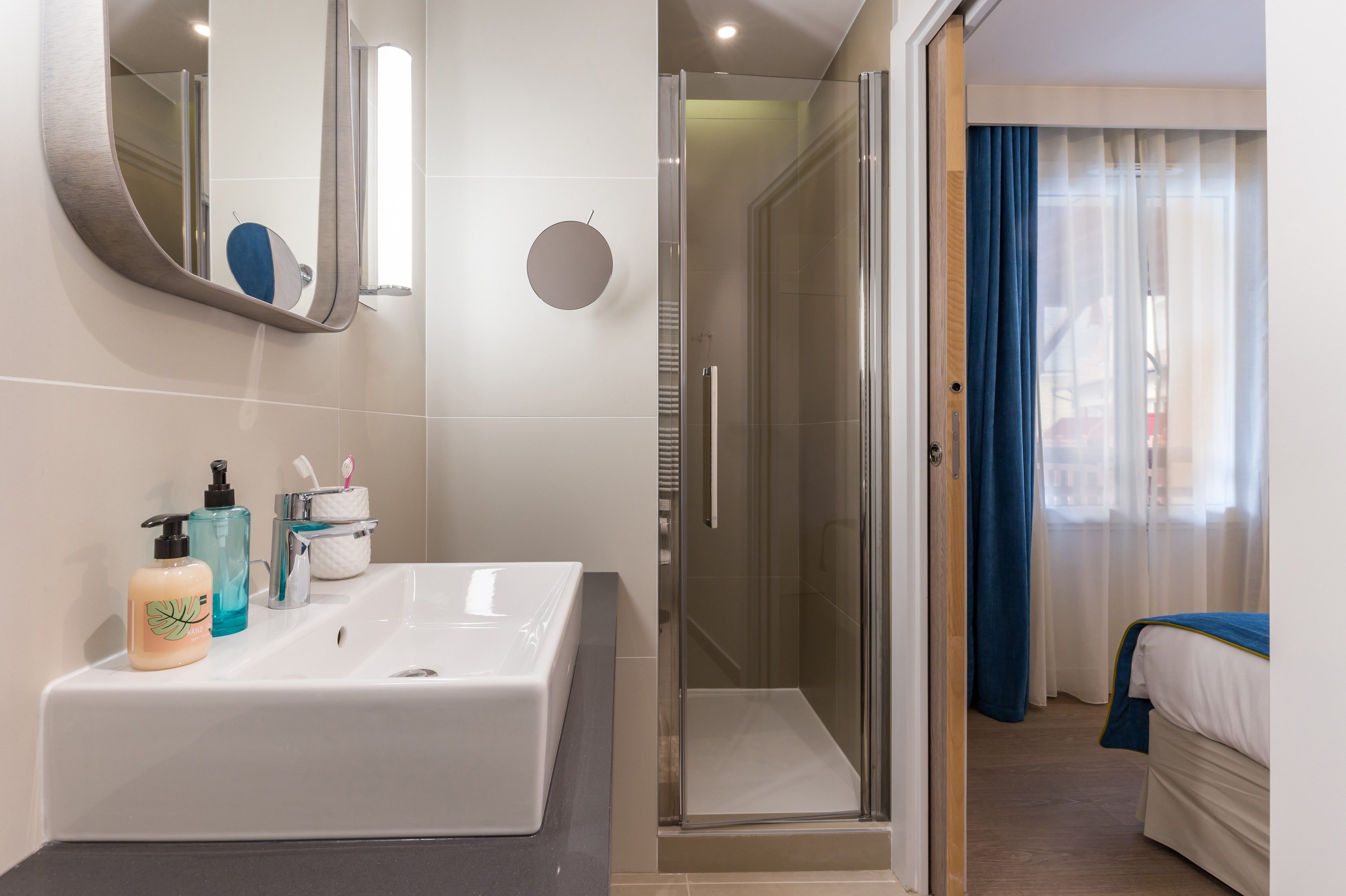 A modern bathroom with a large sink, a mirror, and a shower area.