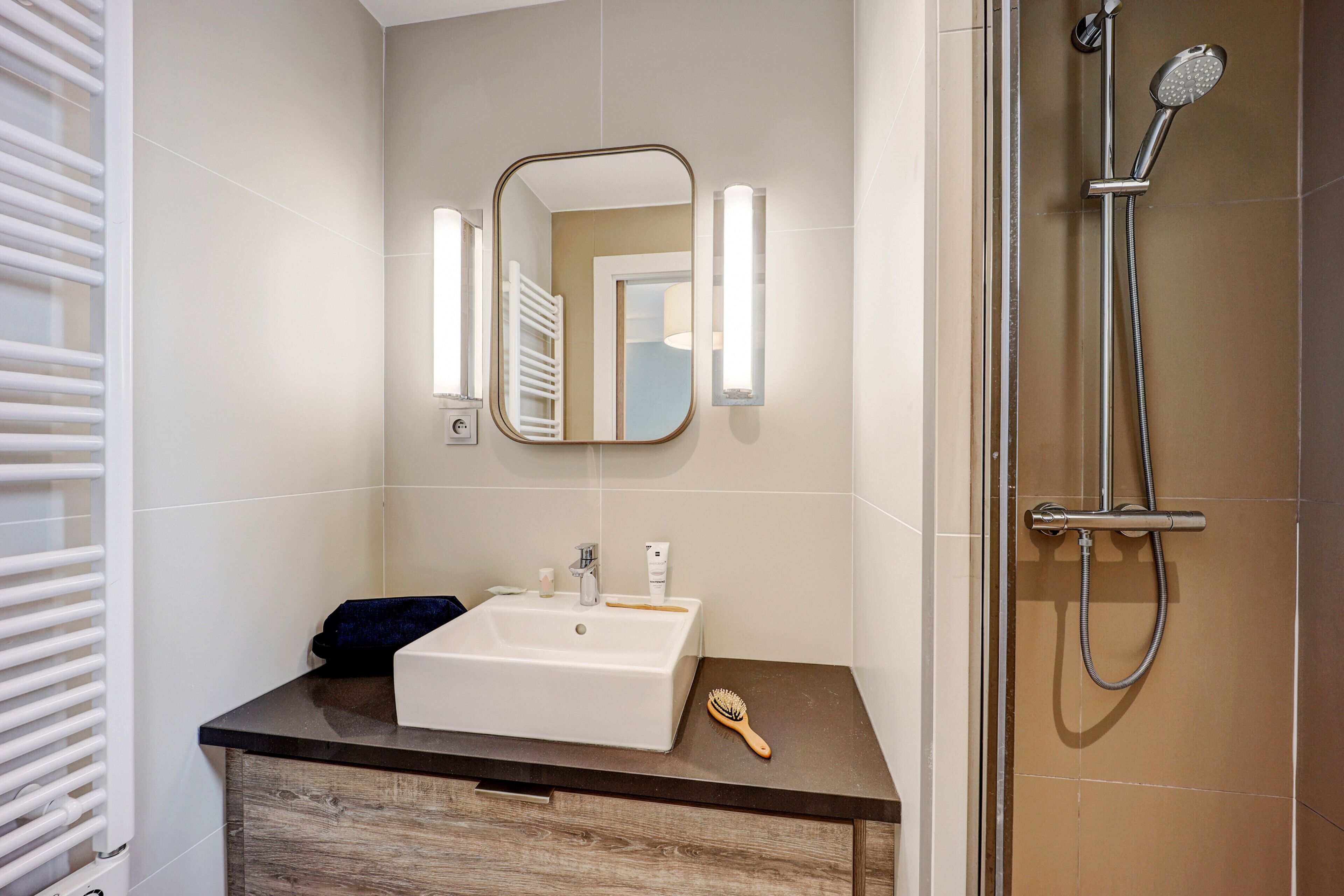 A bathroom with a white sink, a mirror, and a shower.