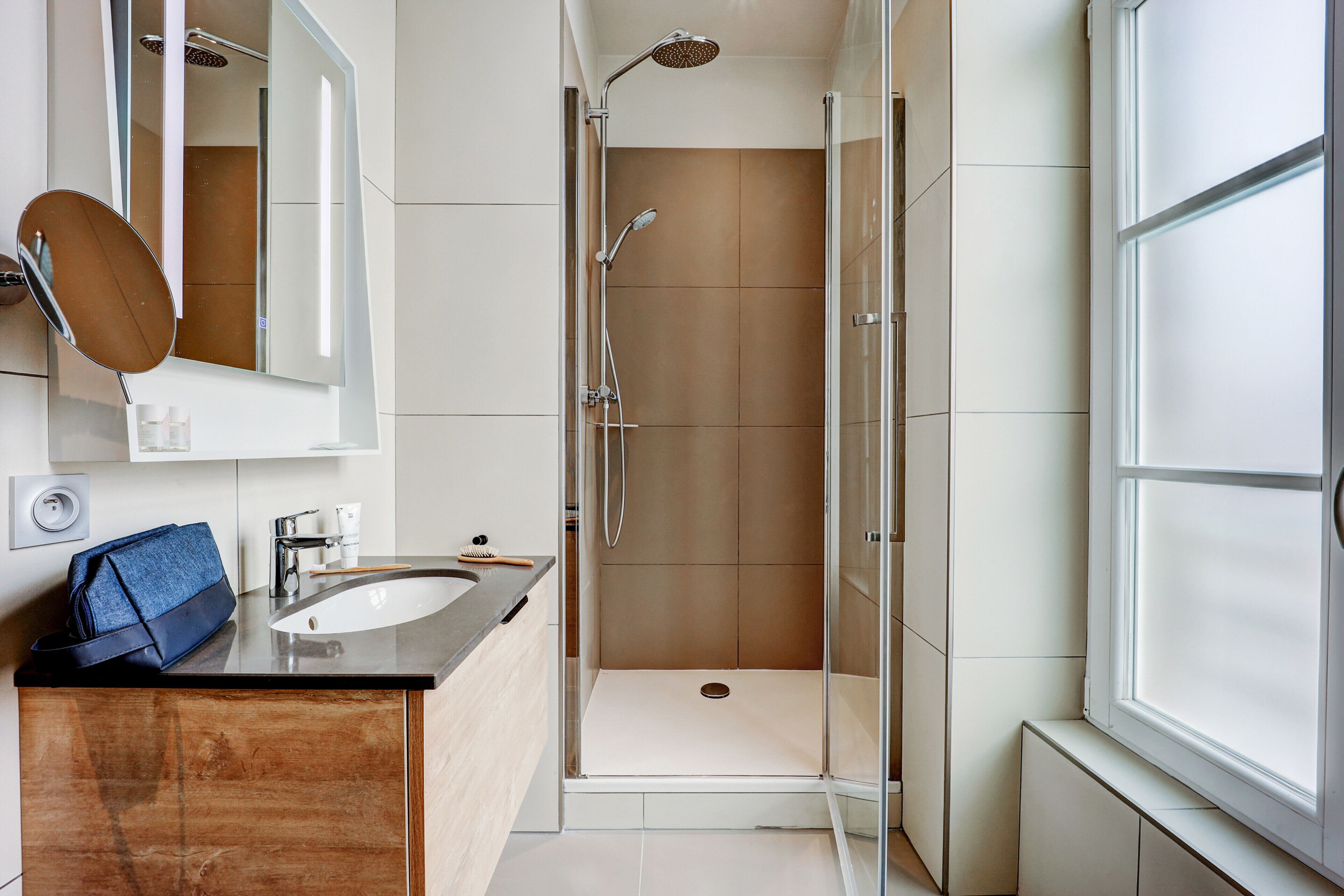 A modern bathroom with a glass-enclosed shower, a sink, and a mirror.