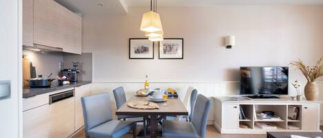Una cocina moderna con comedor, televisor y estantería.