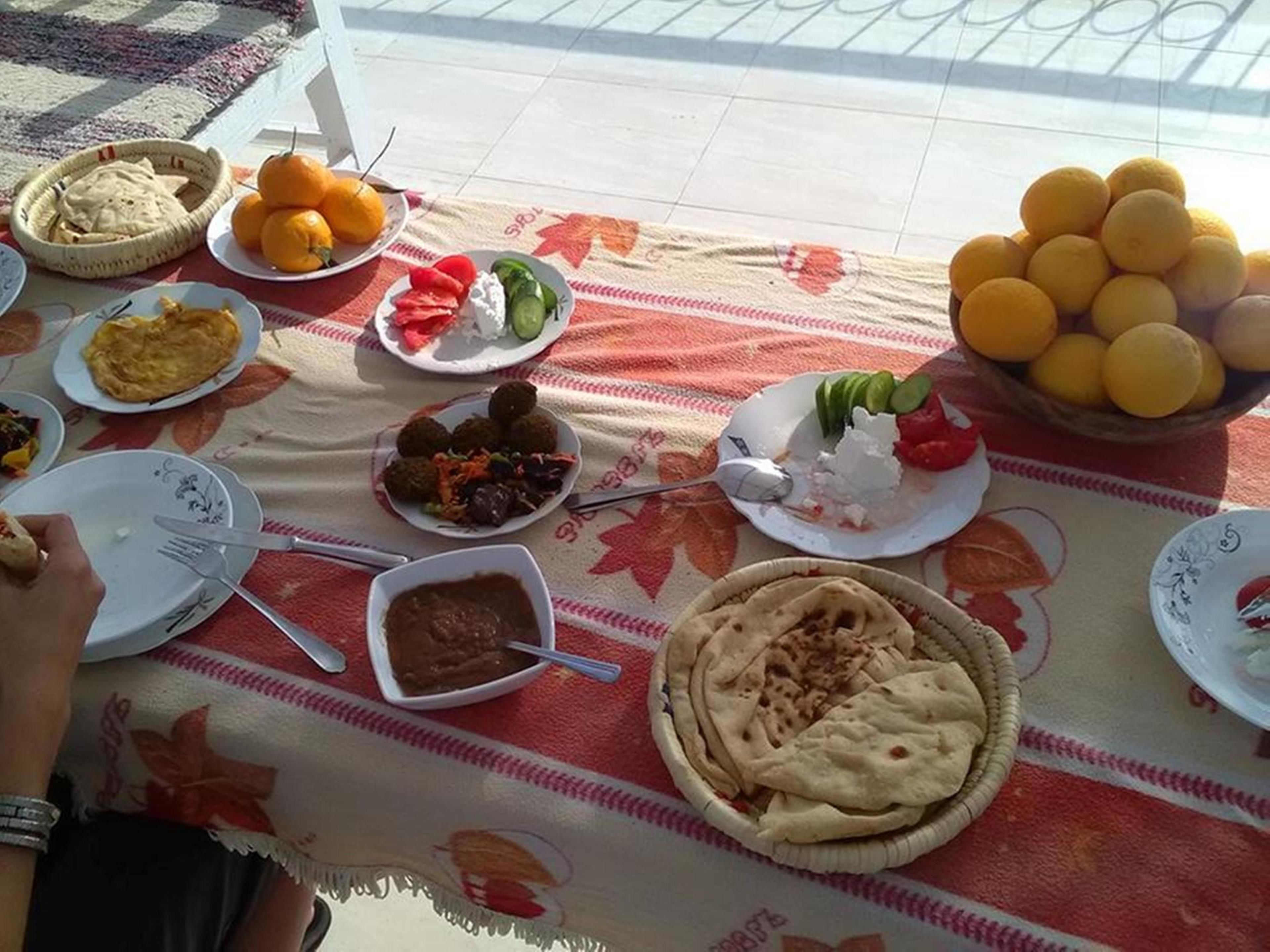 Une table dressée avec divers plats, notamment des galettes, des fruits et un bol de sauce.