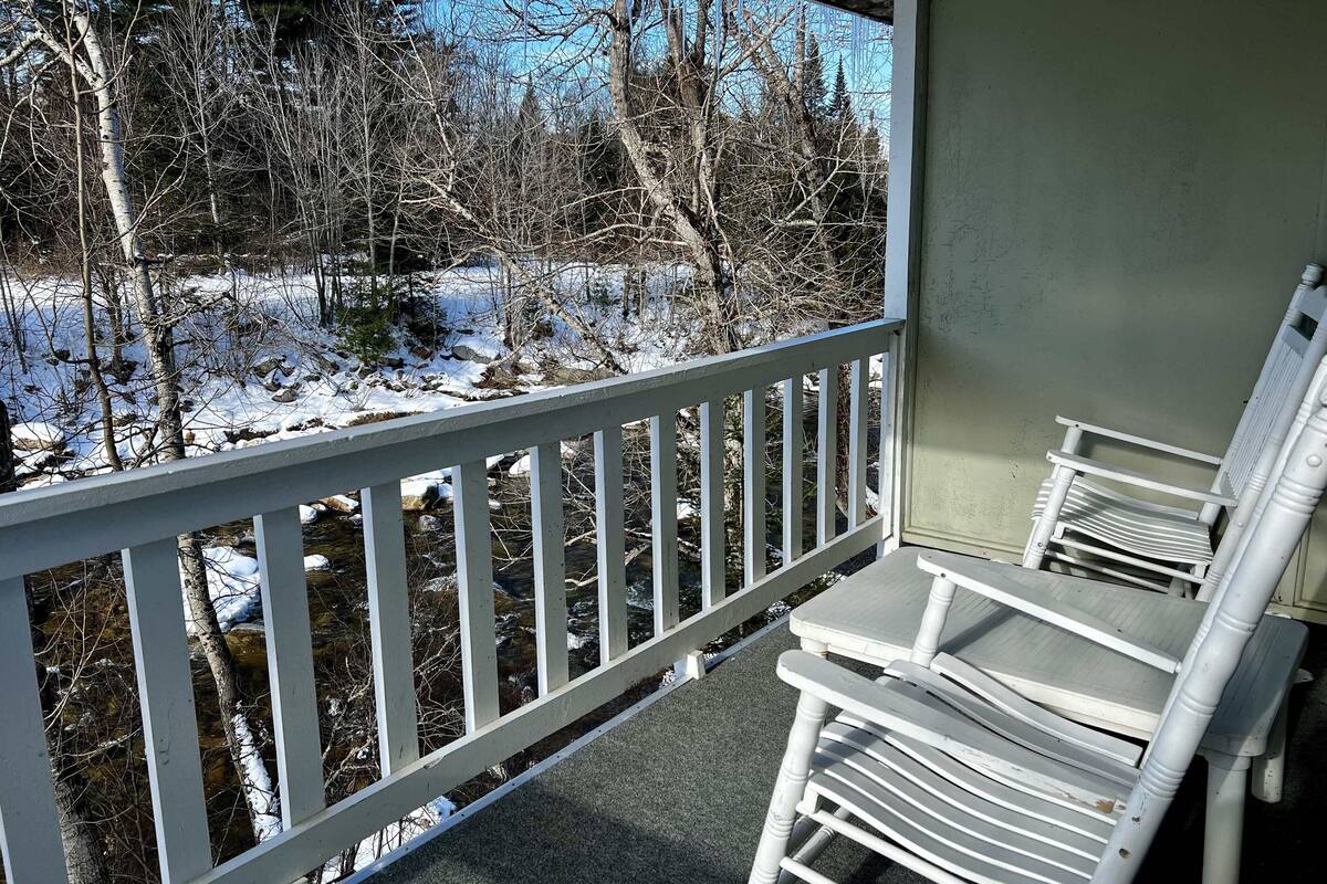 A covered outdoor area with a white railing, a small table, and chairs.