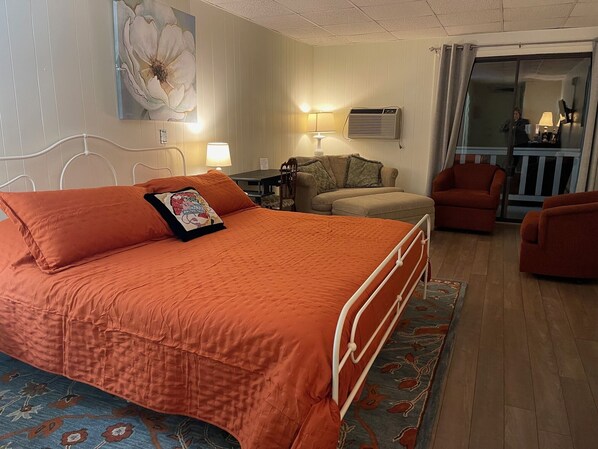 A hotel room with a large bed, a sofa, a chair, a table, and a painting on the wall. - The Wayside Inn (Bethlehem)