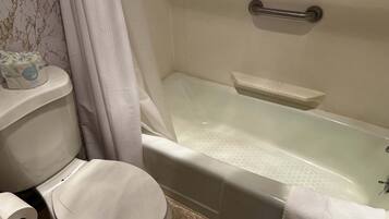 Un baño con inodoro, bañera y cortina de ducha.