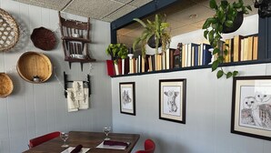 Un comedor con una mesa de madera, sillas rojas y cuadros en las paredes.