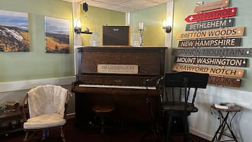 A cozy room with a grand piano, a vintage chair, and a wall adorned with wooden signs indicating various locations.