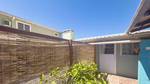 A residential building with a covered patio, a window with a potted plant, and a bamboo fence. - Flores de Bombinhas (Bombinhas)