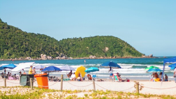 A beach with people, umbrellas, and a clear sky. - Flores de Bombinhas (Bombinhas)