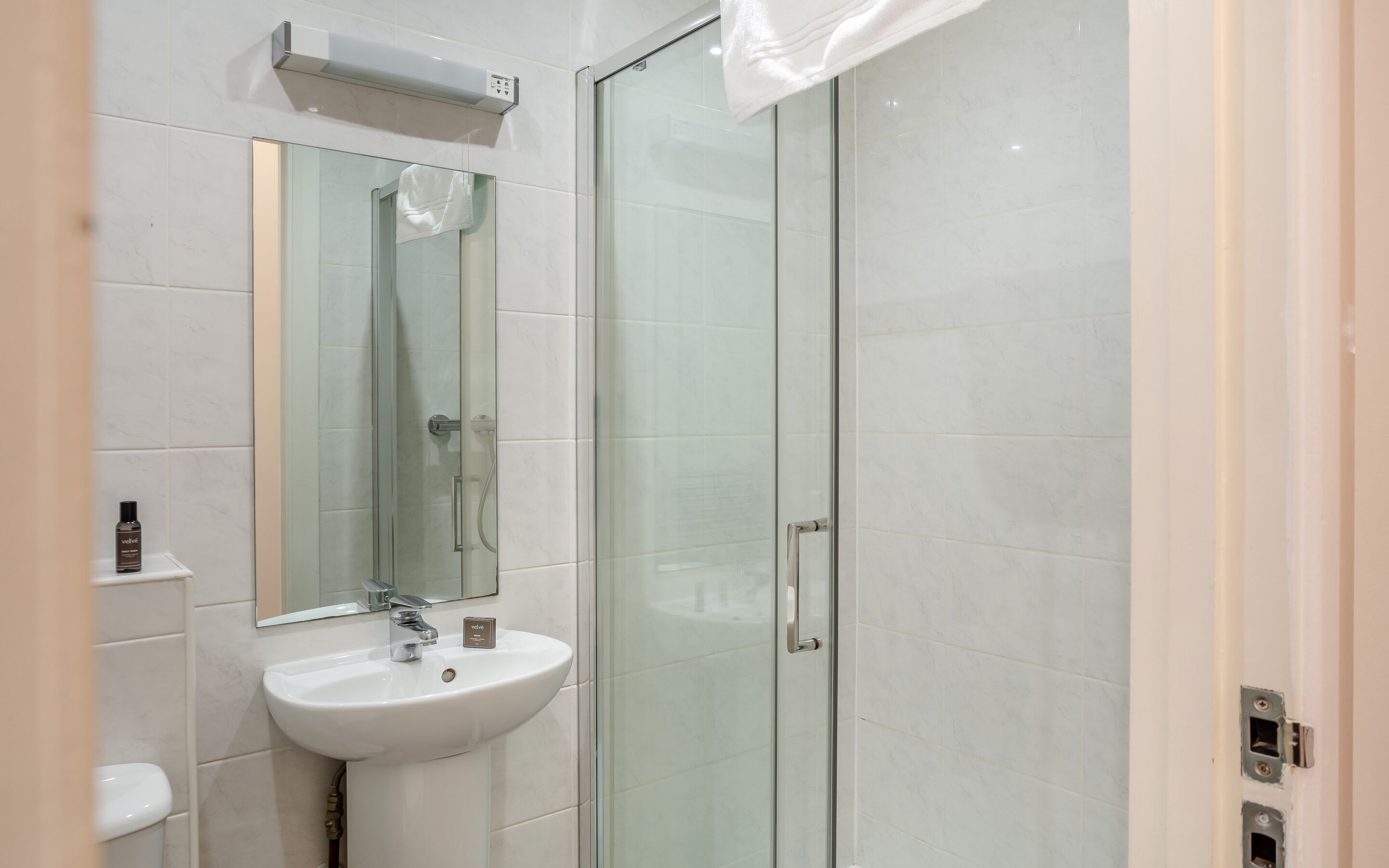 A modern bathroom with a glass shower enclosure, a white sink, and a mirror above the sink.
